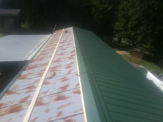 Old rusted panels beside newly installed green metal roofing — Wind Damage Roof Repair by Roofing Brothers in Jamestown